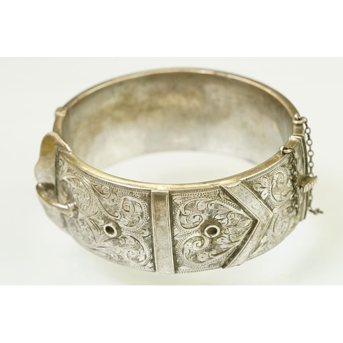 143 - Silver hallmarked buckle bangle handing applied and engraved details with a hinged mechanism. Hallma... 