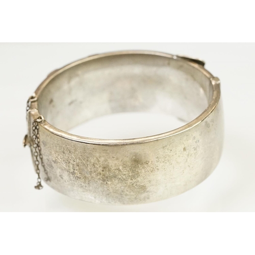 143 - Silver hallmarked buckle bangle handing applied and engraved details with a hinged mechanism. Hallma... 