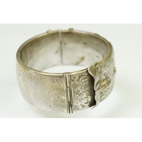 143 - Silver hallmarked buckle bangle handing applied and engraved details with a hinged mechanism. Hallma... 