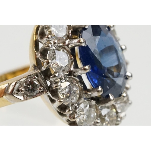 16 - 18ct gold, sapphire and diamond cluster ring being set with an oval mixed but clue sapphire with a h... 