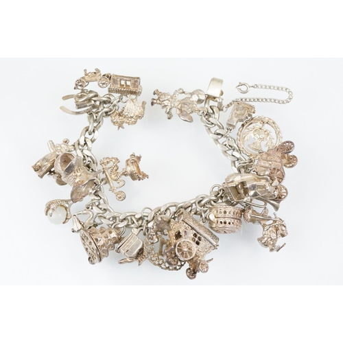 196 - Vintage silver charm bracelet having a curb link chain with box clasp adorned with approximately 21 ... 