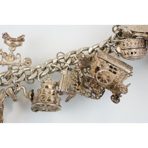 196 - Vintage silver charm bracelet having a curb link chain with box clasp adorned with approximately 21 ... 