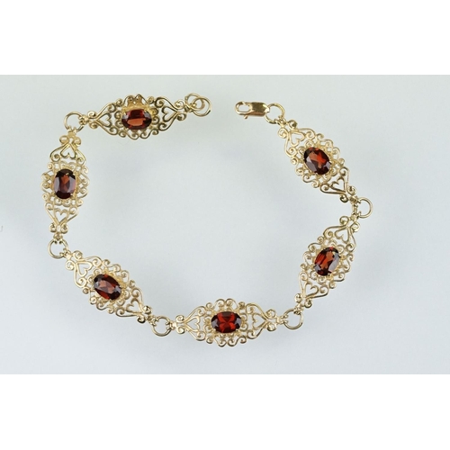 222 - 9ct gold and red stone bracelet having scrolled fret work links with an oval cut red stone to each. ... 