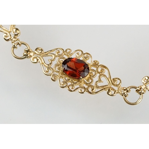 222 - 9ct gold and red stone bracelet having scrolled fret work links with an oval cut red stone to each. ... 