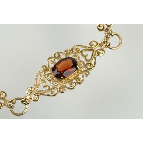 222 - 9ct gold and red stone bracelet having scrolled fret work links with an oval cut red stone to each. ... 