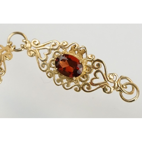 222 - 9ct gold and red stone bracelet having scrolled fret work links with an oval cut red stone to each. ... 