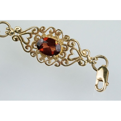 222 - 9ct gold and red stone bracelet having scrolled fret work links with an oval cut red stone to each. ... 