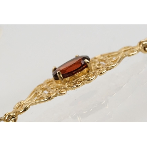 222 - 9ct gold and red stone bracelet having scrolled fret work links with an oval cut red stone to each. ... 