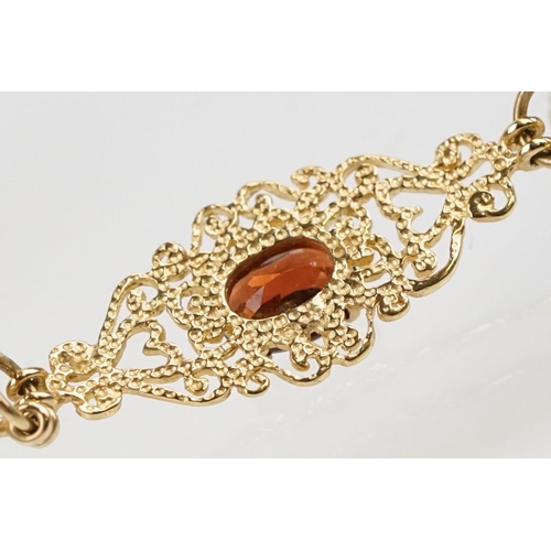 222 - 9ct gold and red stone bracelet having scrolled fret work links with an oval cut red stone to each. ... 