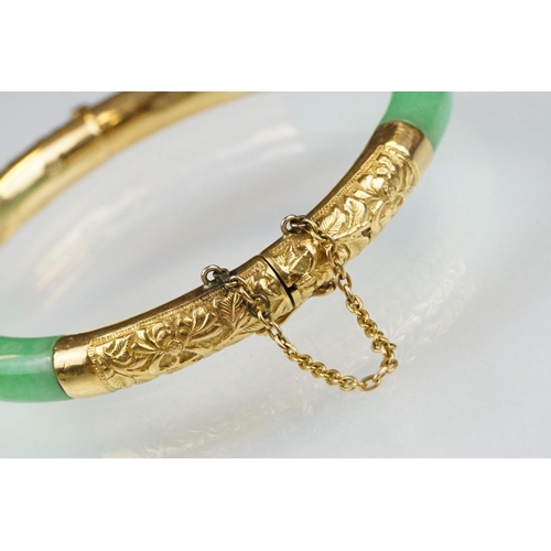 25 - Chinese jade and gold hinged bangle bracelet. The bracelet of round form with gold hinge section and... 