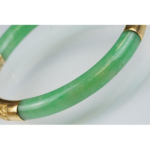 25 - Chinese jade and gold hinged bangle bracelet. The bracelet of round form with gold hinge section and... 