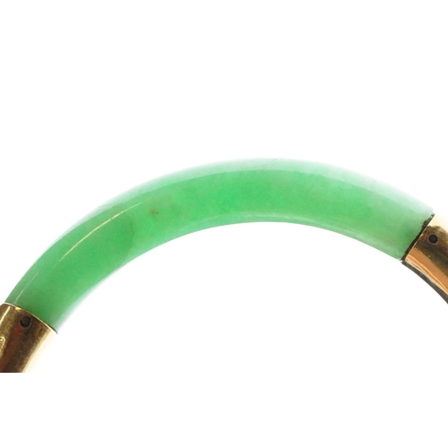 25 - Chinese jade and gold hinged bangle bracelet. The bracelet of round form with gold hinge section and... 