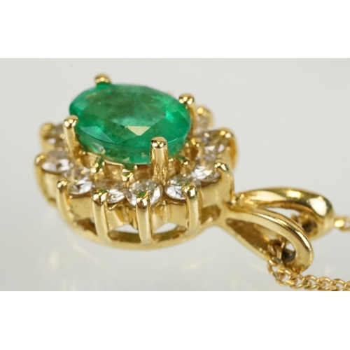 262 - Emerald and diamond halo pendant set to 9ct gold trace chain. The pendant set with an oval cut emera... 