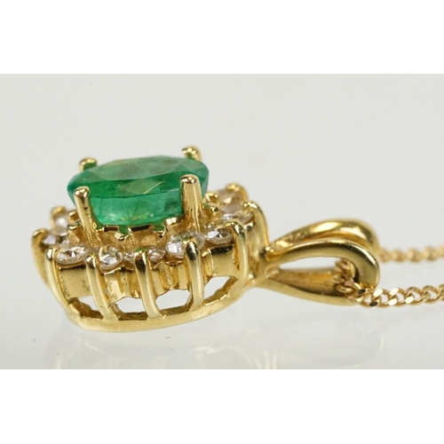 262 - Emerald and diamond halo pendant set to 9ct gold trace chain. The pendant set with an oval cut emera... 