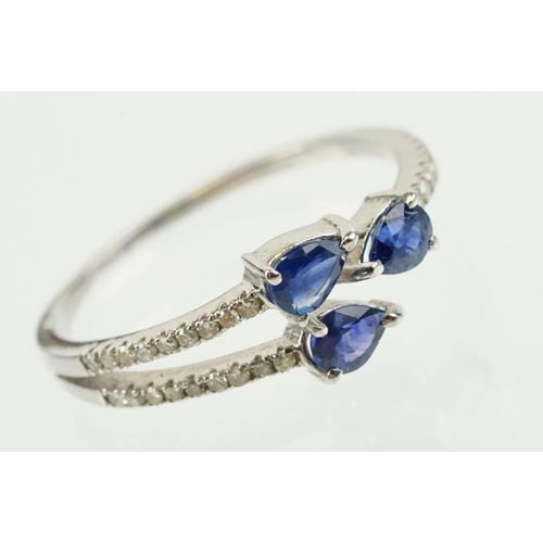 282 - Silver sapphire and diamond ring being set with three pear cut blue sapphires, with diamond accent s... 