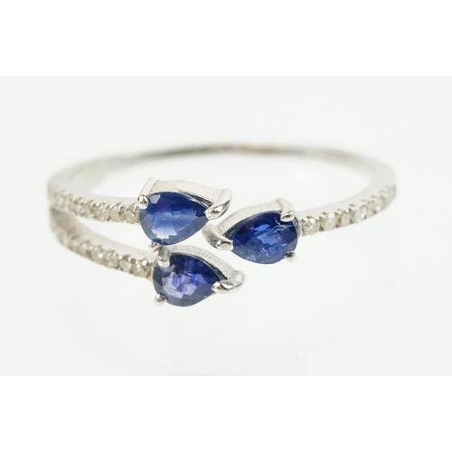 282 - Silver sapphire and diamond ring being set with three pear cut blue sapphires, with diamond accent s... 