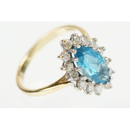 290 - 9ct gold, topaz and diamond cluster ring. The ring being set with a marquise cut blue topaz with a h... 