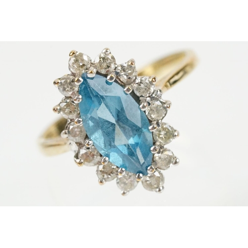 290 - 9ct gold, topaz and diamond cluster ring. The ring being set with a marquise cut blue topaz with a h... 