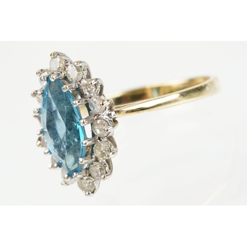 290 - 9ct gold, topaz and diamond cluster ring. The ring being set with a marquise cut blue topaz with a h... 