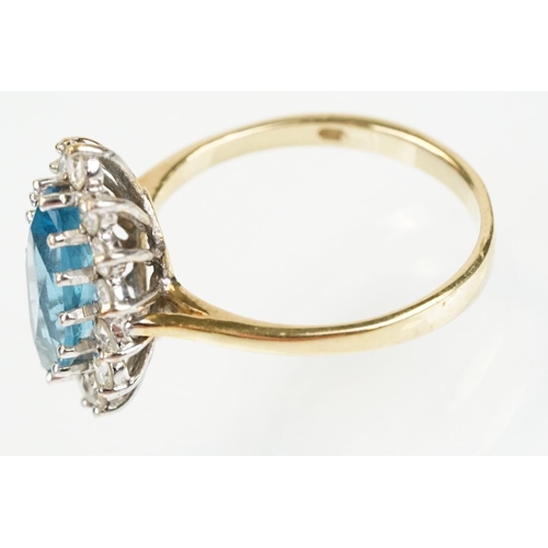 290 - 9ct gold, topaz and diamond cluster ring. The ring being set with a marquise cut blue topaz with a h... 