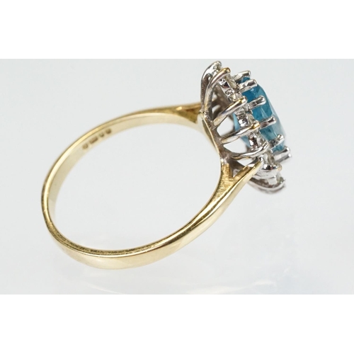 290 - 9ct gold, topaz and diamond cluster ring. The ring being set with a marquise cut blue topaz with a h... 