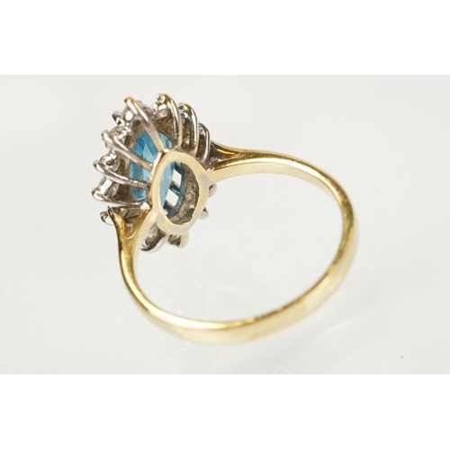 290 - 9ct gold, topaz and diamond cluster ring. The ring being set with a marquise cut blue topaz with a h... 