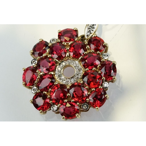 325 - 9ct gold ruby and diamond cluster pendant being set with sixteen oval cut rubies around a centre of ... 