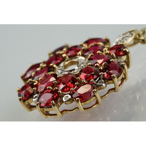 325 - 9ct gold ruby and diamond cluster pendant being set with sixteen oval cut rubies around a centre of ... 