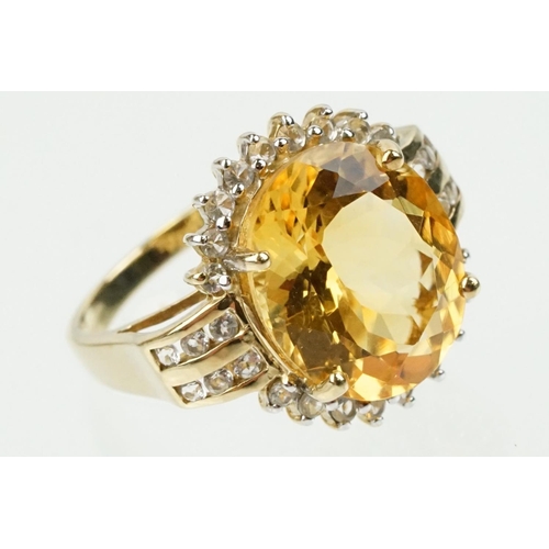 348 - 9ct gold, citrine and clear topaz dress ring. The ring being set with an oval cut citrine surrounded... 