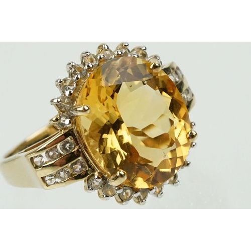 348 - 9ct gold, citrine and clear topaz dress ring. The ring being set with an oval cut citrine surrounded... 