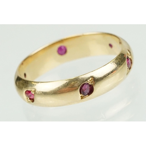 359 - Ruby 14ct yellow gold eternity ring, six small round mixed cut rubies, flush bead set, width approx ... 