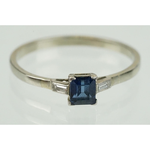 395 - Sapphire and diamond three stone ring set with a step cut blue sapphire flanked by two baguette cut ... 