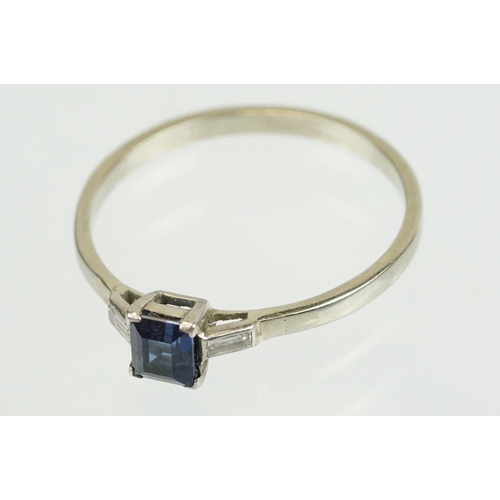 395 - Sapphire and diamond three stone ring set with a step cut blue sapphire flanked by two baguette cut ... 