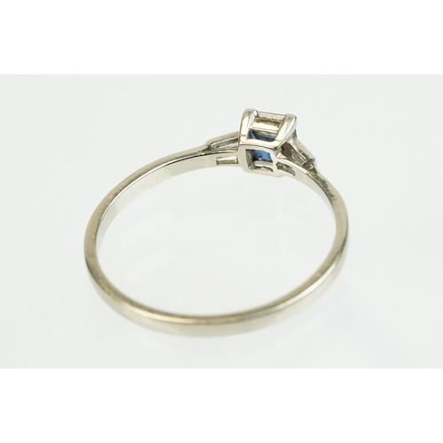 395 - Sapphire and diamond three stone ring set with a step cut blue sapphire flanked by two baguette cut ... 