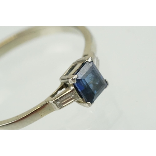 395 - Sapphire and diamond three stone ring set with a step cut blue sapphire flanked by two baguette cut ... 