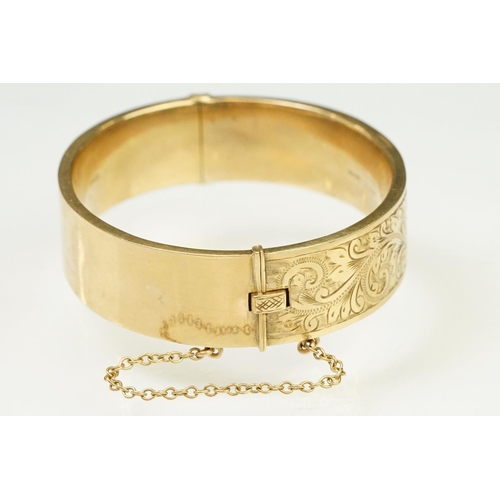 65 - 9ct gold hallmarked bangle bracelet having a hinged mechanism and engraved foliate details to the si... 