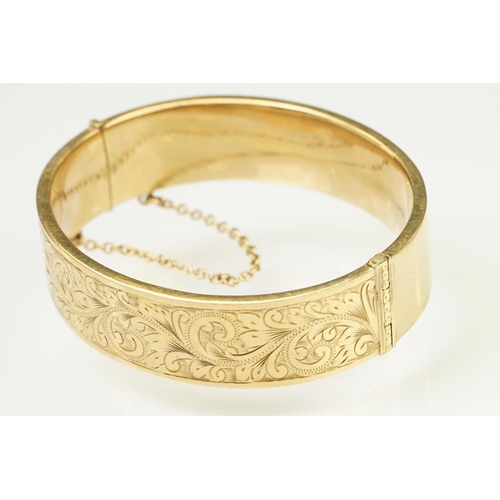 65 - 9ct gold hallmarked bangle bracelet having a hinged mechanism and engraved foliate details to the si... 