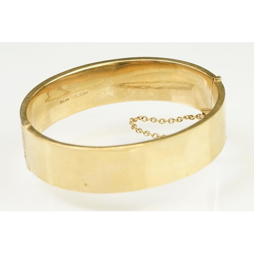 65 - 9ct gold hallmarked bangle bracelet having a hinged mechanism and engraved foliate details to the si... 