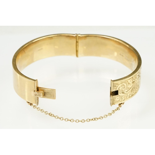 65 - 9ct gold hallmarked bangle bracelet having a hinged mechanism and engraved foliate details to the si... 