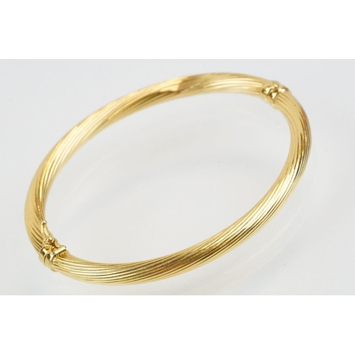 75 - Hallmarked 18ct gold hinged bangle bracelet having a reeded twist design with catch to the clasp. Me... 