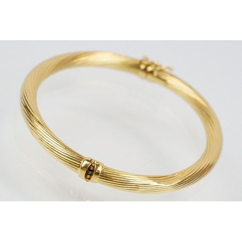 75 - Hallmarked 18ct gold hinged bangle bracelet having a reeded twist design with catch to the clasp. Me... 