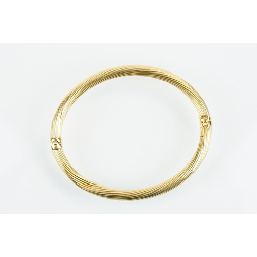 75 - Hallmarked 18ct gold hinged bangle bracelet having a reeded twist design with catch to the clasp. Me... 