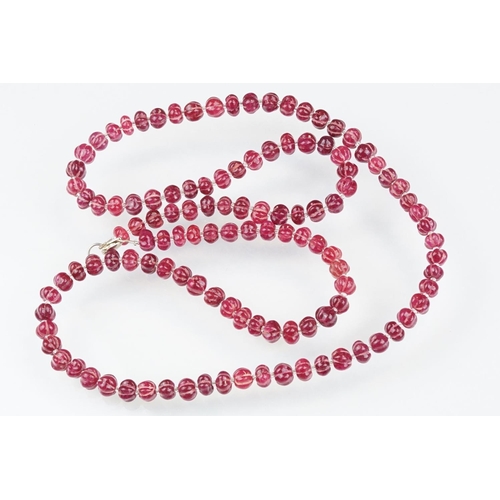 98 - Carved ruby beaded necklace, each bead carved with ridges to the sides and glass spacer beads. Silve... 