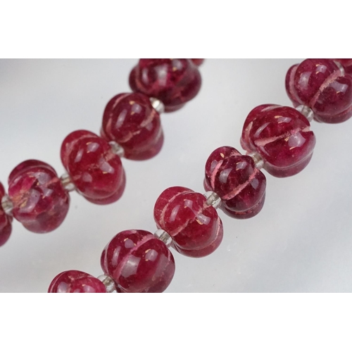 98 - Carved ruby beaded necklace, each bead carved with ridges to the sides and glass spacer beads. Silve... 