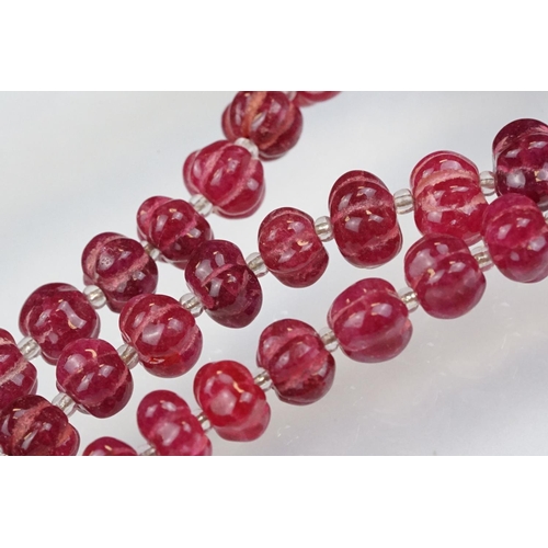 98 - Carved ruby beaded necklace, each bead carved with ridges to the sides and glass spacer beads. Silve... 