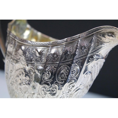 653 - 18th Century George III Scottish silver cream jug of helmet form having repousse scrolled detailing ... 