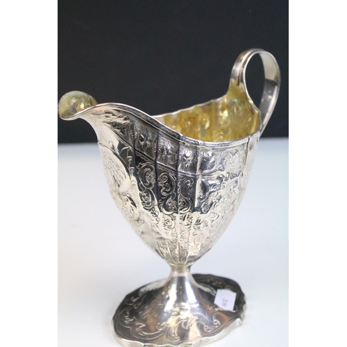 653 - 18th Century George III Scottish silver cream jug of helmet form having repousse scrolled detailing ... 