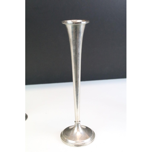 673 - Two silver stem vases together with a pair of silver candlesticks. Both stem vases marked sterling (... 