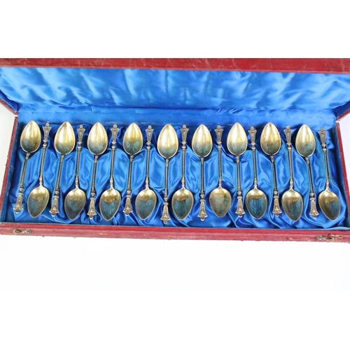 185 - A cased set of eighteen teaspoons, lions head to finials, gilt white metal stamped .830.