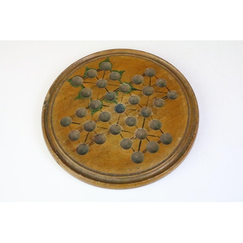 191 - An antique carved wooden solitaire board complete with antique marbles.